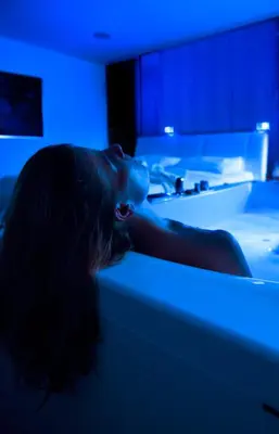 a woman laying on a bed in a room with blue lights at Villa EVA in Dobrovo