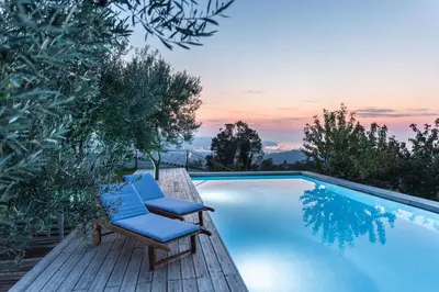 a couple of chairs sitting on a deck next to a swimming pool at Villa EMI in Zgornje Škofije
