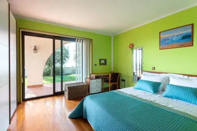 a green bedroom with a bed and a sliding glass door at Villa EMI in Zgornje Škofije