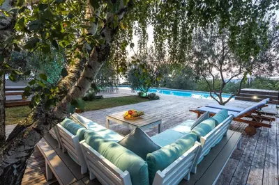 a patio with a couch and a table under a tree at Villa EMI in Zgornje Škofije