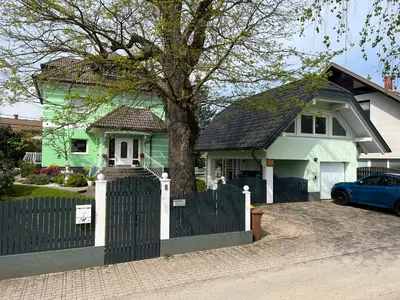 a green house with a fence and a tree at Vila Lesce with heated outdoor pool in Lesce