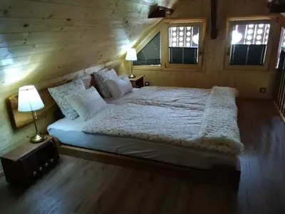 a large bed in a wooden room with two lamps at Barn House MM in Bled