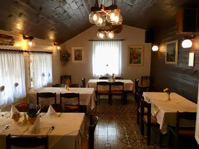 a restaurant with white tables and chairs and a chandelier at Guest House Atelšek in Rečica ob Savinji