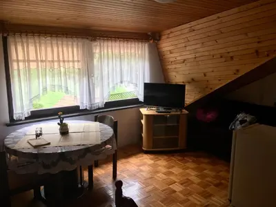 a room with a table and a tv in a attic at Guest House Atelšek in Rečica ob Savinji