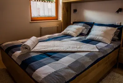 a bed with a blue and white blanket and pillows at Apartments BBI in Luče
