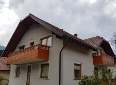 a white house with wooden balconies on it at Apartments BBI in Luče