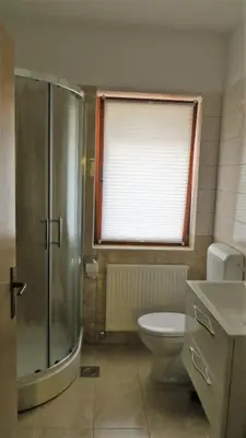 a bathroom with a shower and a toilet and a window at Holiday House Kanalec in Drežnica