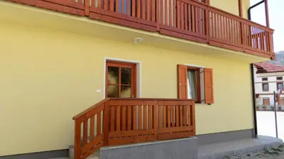 a house with a wooden balcony and a window at Holiday House Kanalec in Drežnica