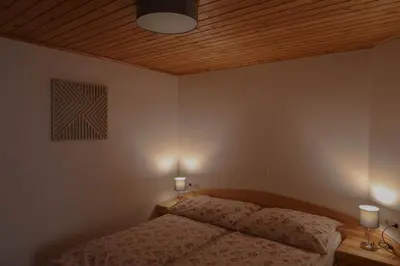 a bedroom with a bed with two lamps and a wooden ceiling at Mountain View Apartments - Pr` Potovcn`k in Dovje