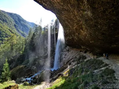 a waterfall in a canyon with people standing next to it at Mountain View Apartments - Pr` Potovcn`k in Dovje