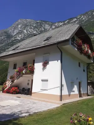 a white building with flowers on the balconies at Apartma pod Rožem in Soča
