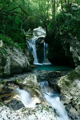 a waterfall in the middle of a river with rocks at Apartma pod Rožem in Soča