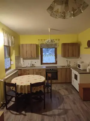 a kitchen with a table and a kitchen with yellow walls at Apartma pod Rožem in Soča