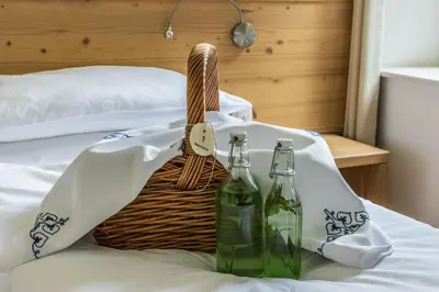 a basket and two bottles on a bed at Boutique rooms Pri Rogovilcu in Solčava