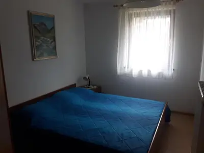 a bedroom with a blue bed and a window at Apartma Bel in Žaga
