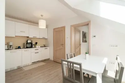 a kitchen with white cabinets and a white table at Apartments Villa Vesna Pokljuka in Goreljek
