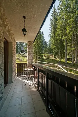 a porch with a table and chairs on a deck at Apartments Villa Vesna Pokljuka in Goreljek