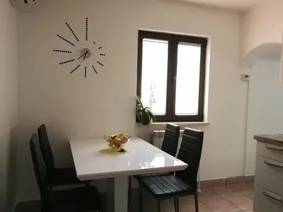 a dining room table with chairs and a clock on the wall at House Čeh in Črni Kal