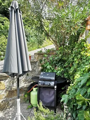 an umbrella sitting next to a grill and a smoker at House Čeh in Črni Kal