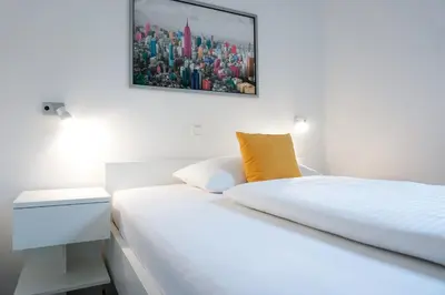 a white bedroom with a bed and a picture on the wall at Guest House Mlada lipa in Maribor