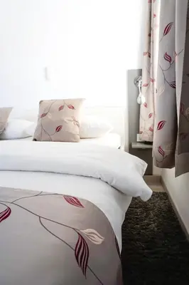 a bedroom with a bed with white sheets and a window at Guest House Mlada lipa in Maribor