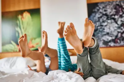 two girls laying on a bed with their feet in the air at Pohorje Village Wellbeing Resort - Forest Hotel Videc in Pohorje