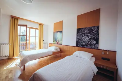 a hotel room with two beds and a window at Pohorje Village Wellbeing Resort - Forest Hotel Videc in Pohorje