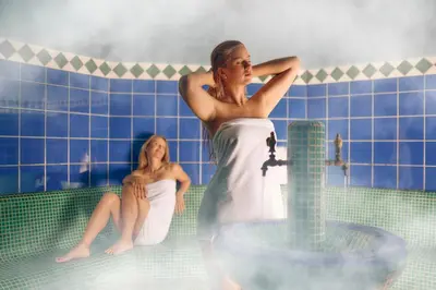 two women in a bath tub with a sink at Pohorje Village Wellbeing Resort - Forest Hotel Videc in Pohorje