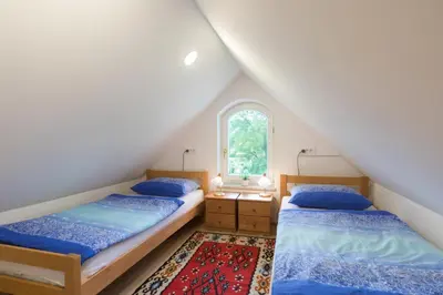 two beds in a attic bedroom with a window at Vila Katja in Bled