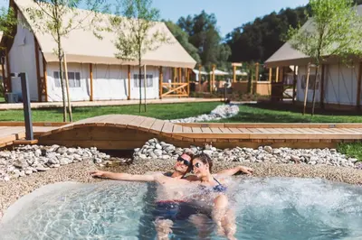 two people in a swimming pool in a backyard at Glamping Olimia Adria village in Podčetrtek