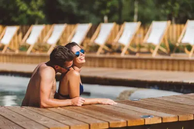 a man and woman sitting in a swimming pool at Glamping Olimia Adria village in Podčetrtek