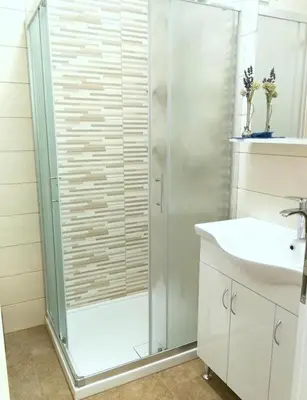 a white bathroom with a shower and a sink at Apartma AS in Lesce