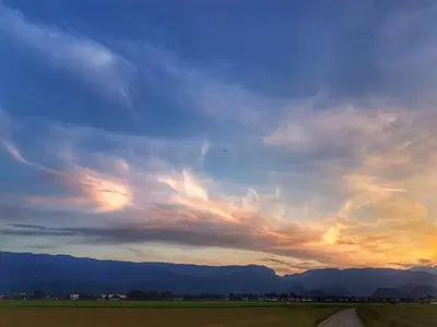 a cloudy sky over a field with a dirt road at Apartma AS in Lesce