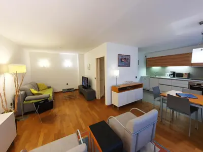 a living room with a couch and a table and a kitchen at Apartment Eva Tour As Ljubljana in Ljubljana