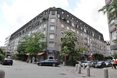a large building with cars parked in front of it at Apartment Eva Tour As Ljubljana in Ljubljana