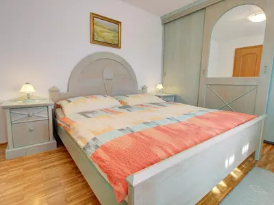 a bedroom with a large bed with an orange blanket at Apartments Orazem in Bled
