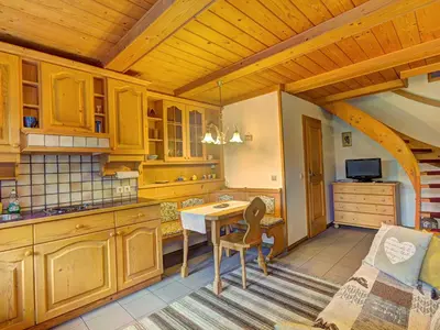 a kitchen with wooden cabinets and a table and a couch at Apartments Orazem in Bled