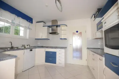 a kitchen with white cabinets and blue accents at Family Villa Bled in Bled