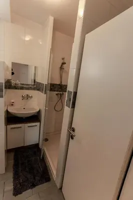 a bathroom with a shower and a sink and a door at Apartment Gondola in Maribor