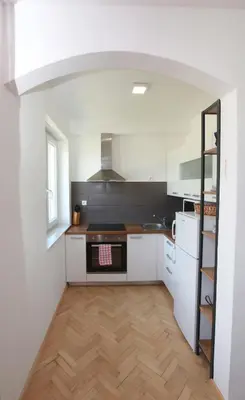 a kitchen with white appliances and a wooden floor at Apartment Gondola in Maribor