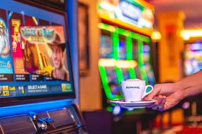 a person holding a coffee cup on a slot machine at Casino & Hotel ADMIRAL Skofije in Zgornje Škofije