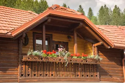 a wooden cabin with flowers on a balcony at Apartments & Chalet Jurček in Luče