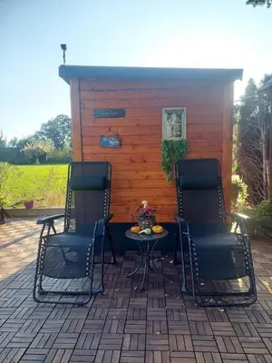 two chairs and a table in front of a cabin at Apartma Žirovnik in Cerklje na Gorenjskem
