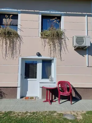a red chair and a table in front of a building at Apartma Žirovnik in Cerklje na Gorenjskem