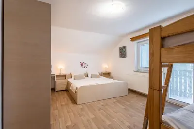 a white bedroom with a bed and a window at Apartments Orel in Mozirje