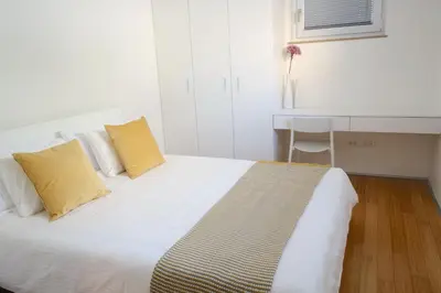 a white bed with two yellow pillows in a room at Sensei apartment in Ljubljana