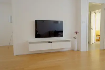 a living room with a tv on a white wall at Sensei apartment in Ljubljana