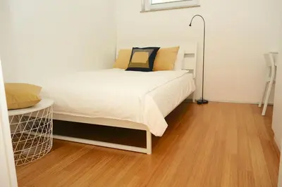 a bedroom with a bed and a wooden floor at Sensei apartment in Ljubljana