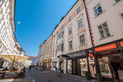a street with buildings and people walking down a street at Elegant Central Apartment in Ljubljana
