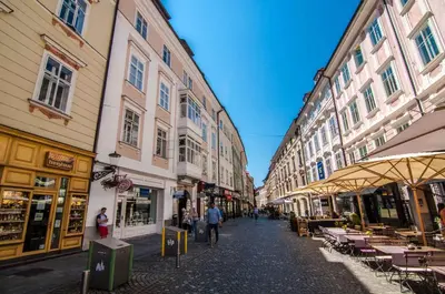 a street with buildings and tables and people walking down it at Elegant Central Apartment in Ljubljana